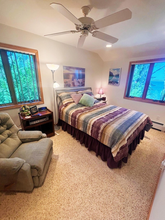 bedroom featuring multiple windows, a baseboard heating unit, ceiling fan, and vaulted ceiling