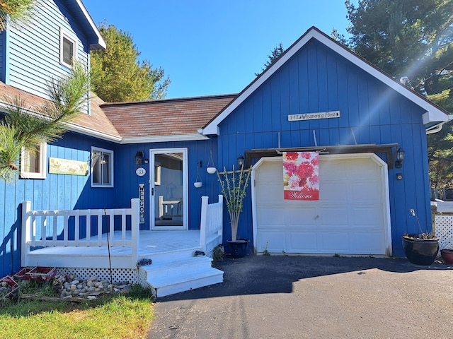 view of front of house with aphalt driveway, a garage, and a shingled roof