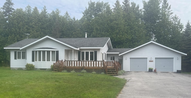 view of front of property featuring an attached garage, roof with shingles, a deck, and a front lawn