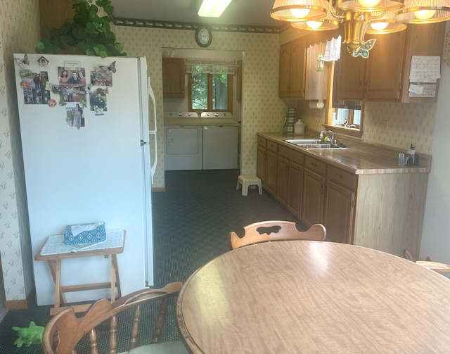 kitchen featuring wallpapered walls, separate washer and dryer, freestanding refrigerator, a sink, and light countertops