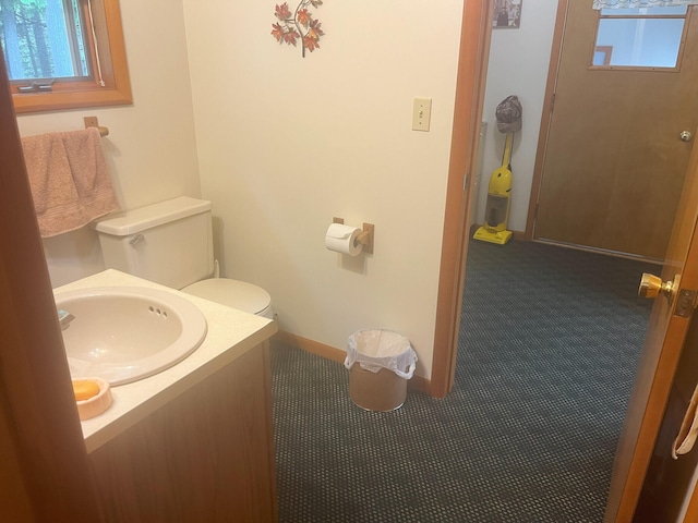 half bath with baseboards, toilet, and vanity