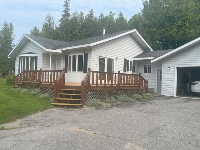 rear view of property featuring aphalt driveway, a shingled roof, and a garage