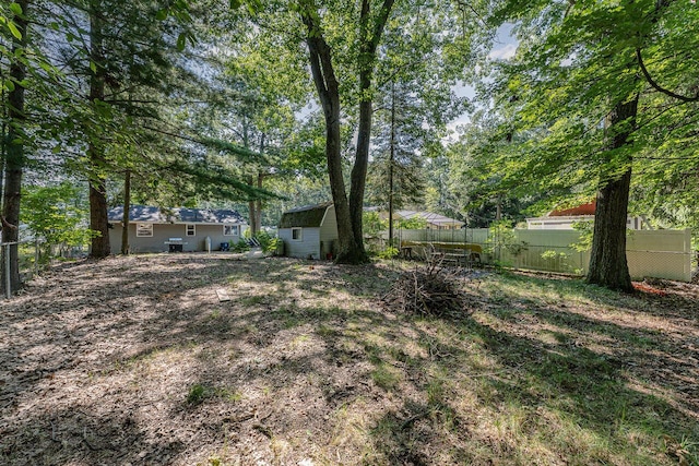 view of yard featuring fence, an outdoor structure, and a storage unit