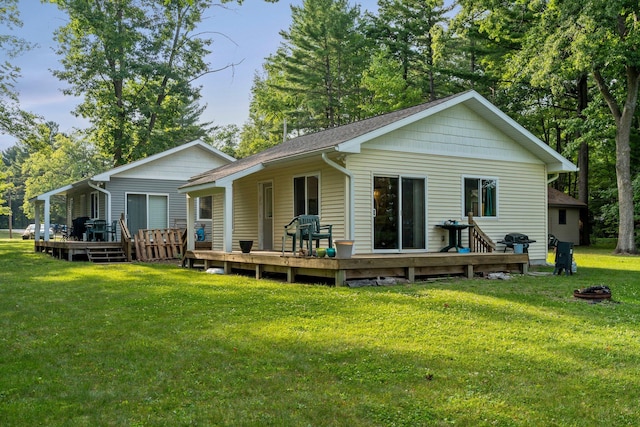 rear view of property featuring a wooden deck and a lawn