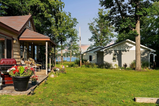 3551 W Otsego Lake Dr, Gaylord, MI 49735 - yard at dusk with a water view and a patio area