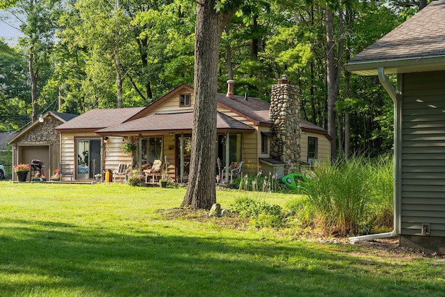 3551 W Otsego Lake Dr, Gaylord, MI 49735 - back of house with a yard, a chimney, and a garage