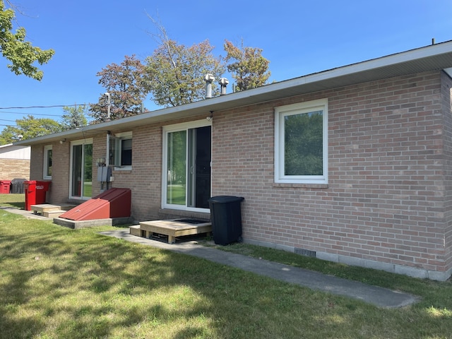 rear view of property with a lawn, brick siding, and crawl space