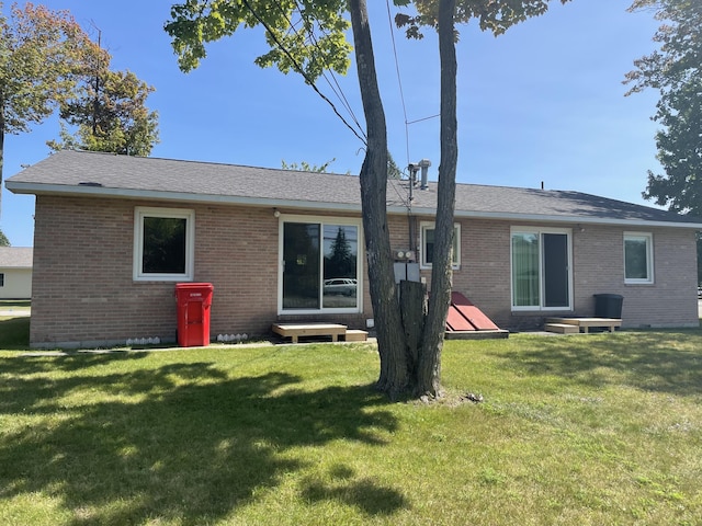 back of property featuring a lawn and brick siding