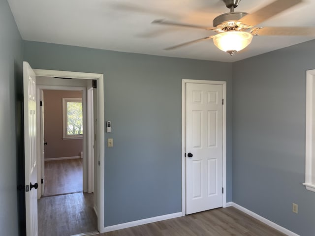 unfurnished bedroom featuring a ceiling fan, wood finished floors, and baseboards