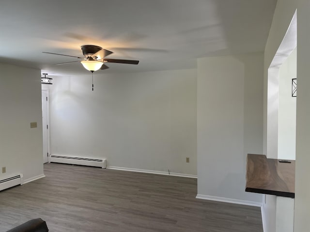 unfurnished living room featuring a baseboard heating unit, wood finished floors, baseboards, and ceiling fan