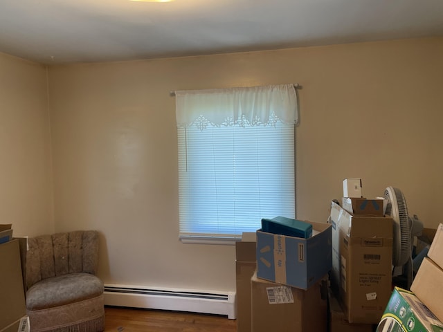 living area featuring a baseboard heating unit and wood finished floors