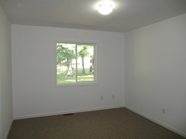 carpeted spare room with visible vents and baseboards