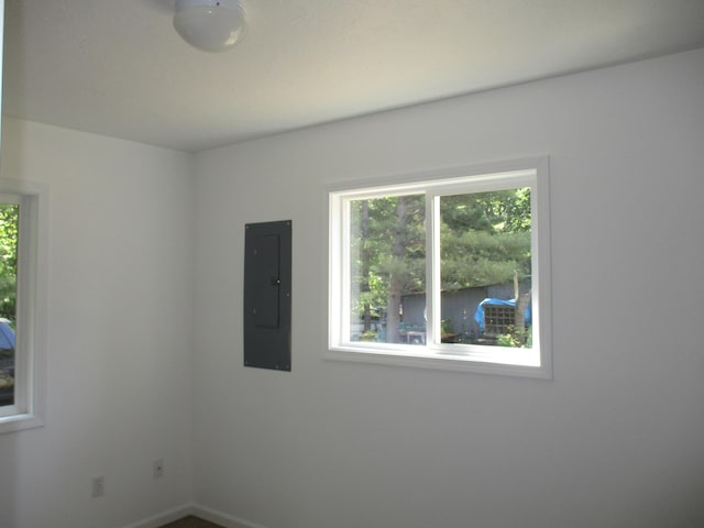 spare room with electric panel and baseboards