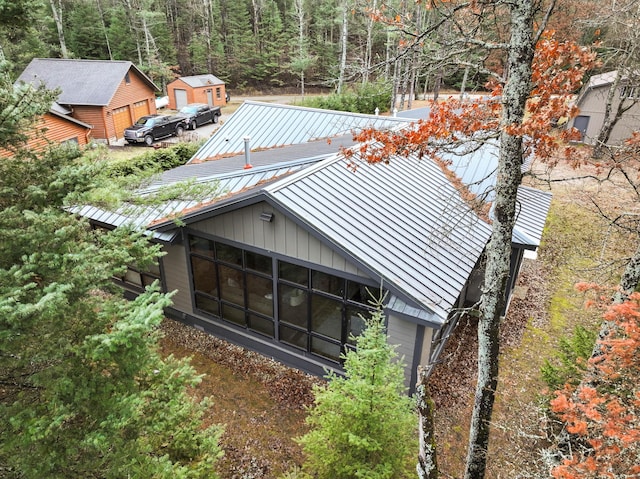 exterior space with an outbuilding, a wooded view, a standing seam roof, a sunroom, and metal roof