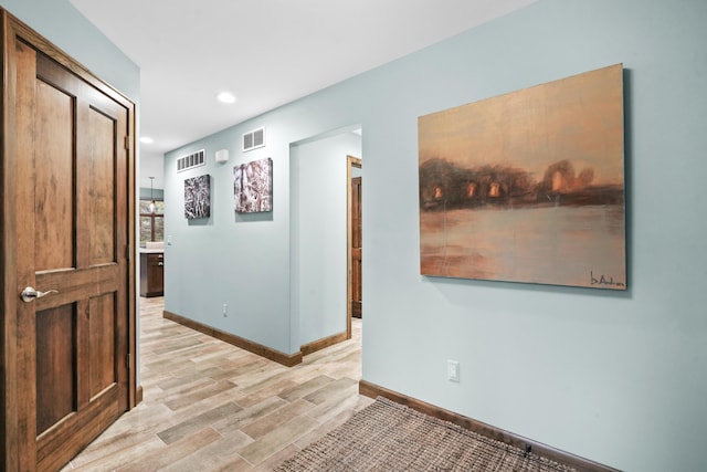 hallway with recessed lighting, light wood-style floors, visible vents, and baseboards