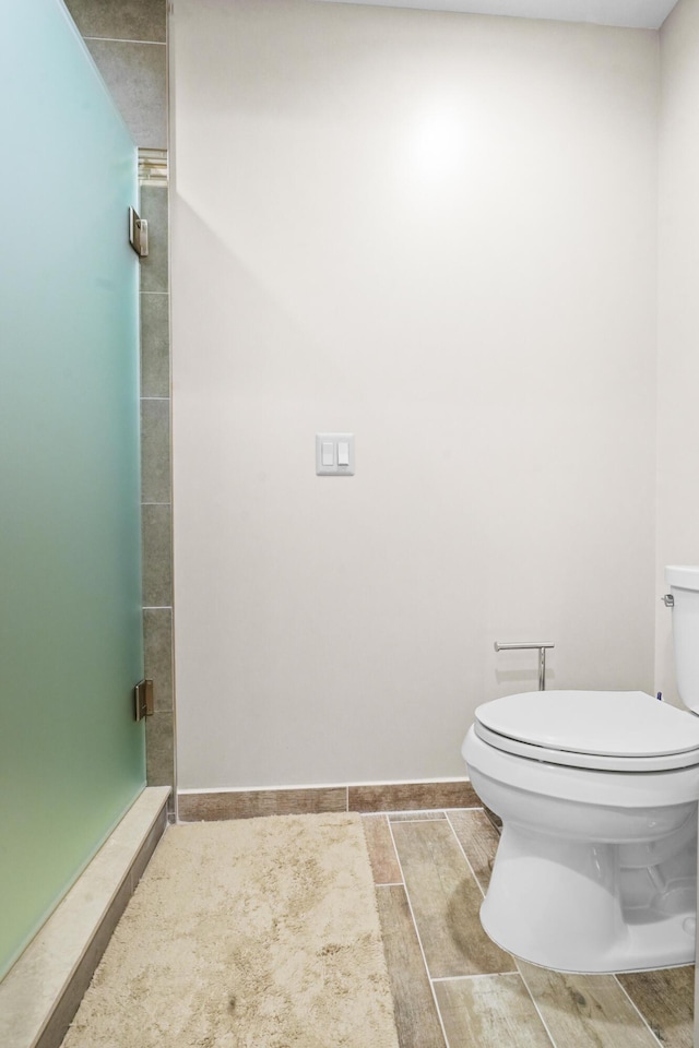 full bath featuring a shower stall, toilet, and baseboards