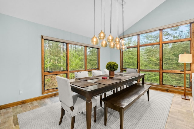 dining room with light wood-type flooring, baseboards, a notable chandelier, and vaulted ceiling