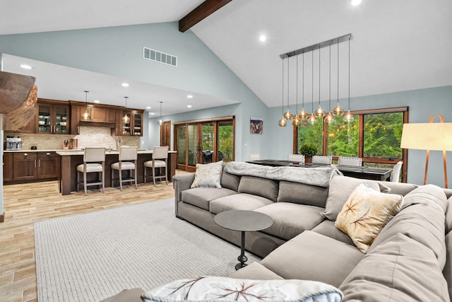 living area with visible vents, beam ceiling, high vaulted ceiling, recessed lighting, and light wood finished floors