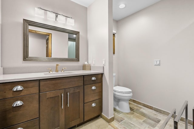 bathroom featuring toilet, vanity, and baseboards