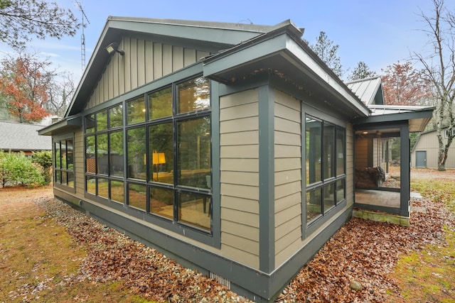 view of side of home with board and batten siding, a sunroom, and metal roof