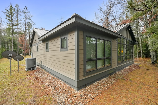 view of property exterior with central AC unit and metal roof