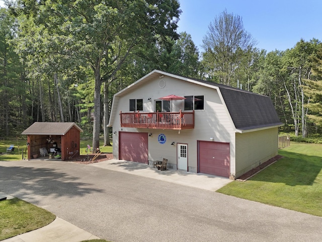 view of front of house with a gambrel roof, a front lawn, and a shingled roof