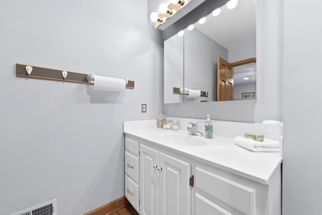 bathroom featuring visible vents, baseboards, and vanity