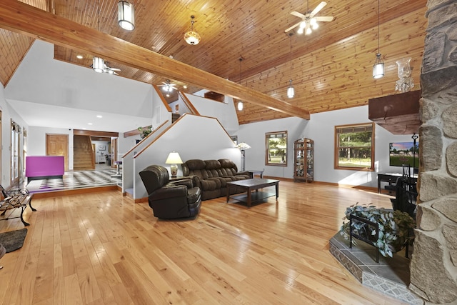 living room with beam ceiling, high vaulted ceiling, hardwood / wood-style flooring, stairway, and ceiling fan