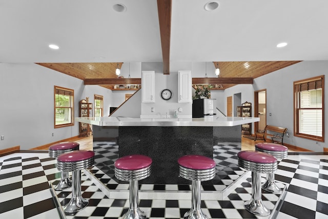 kitchen featuring white cabinetry, beam ceiling, wood ceiling, and light floors