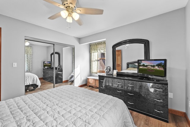 bedroom with a closet, baseboards, wood finished floors, and a ceiling fan