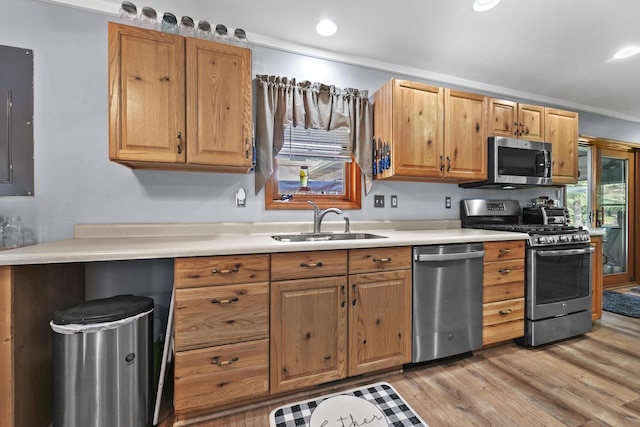 kitchen with light wood finished floors, a sink, recessed lighting, stainless steel appliances, and light countertops