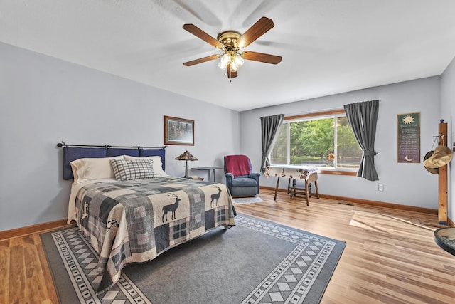 bedroom featuring ceiling fan, baseboards, and wood finished floors