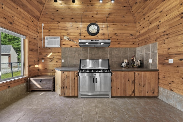 kitchen featuring dark countertops, tile patterned floors, ventilation hood, an AC wall unit, and stainless steel gas stove