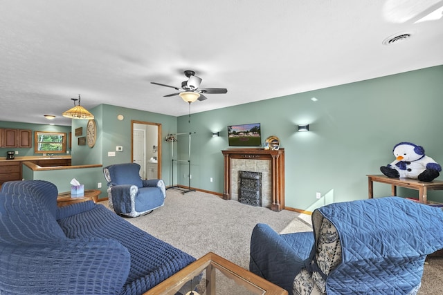 carpeted living room featuring visible vents, baseboards, a ceiling fan, and a fireplace