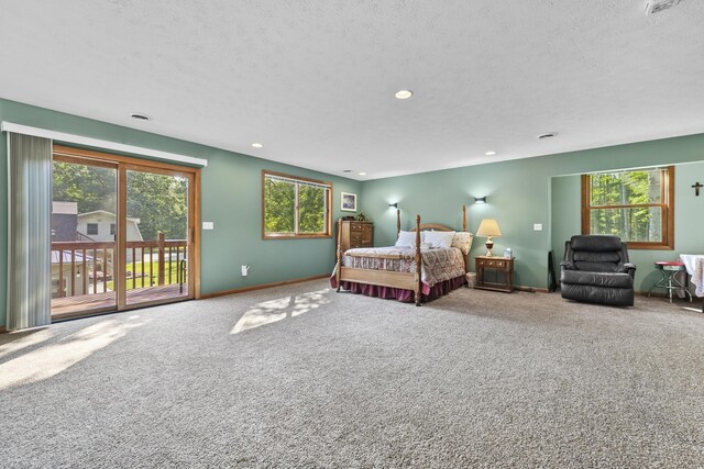 carpeted bedroom with multiple windows, a textured ceiling, and access to outside