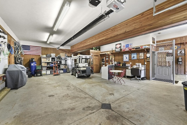 garage with a workshop area, wooden walls, and a garage door opener