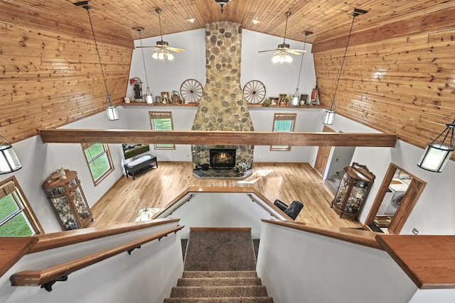 staircase featuring wood ceiling, a stone fireplace, wood finished floors, high vaulted ceiling, and a ceiling fan