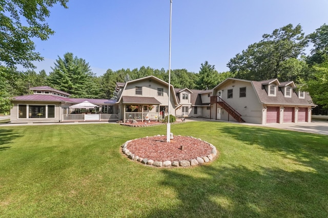 back of property featuring stairs, a garage, a yard, and a gambrel roof