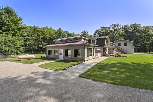 view of front facade with a gambrel roof, metal roof, a front lawn, and fence