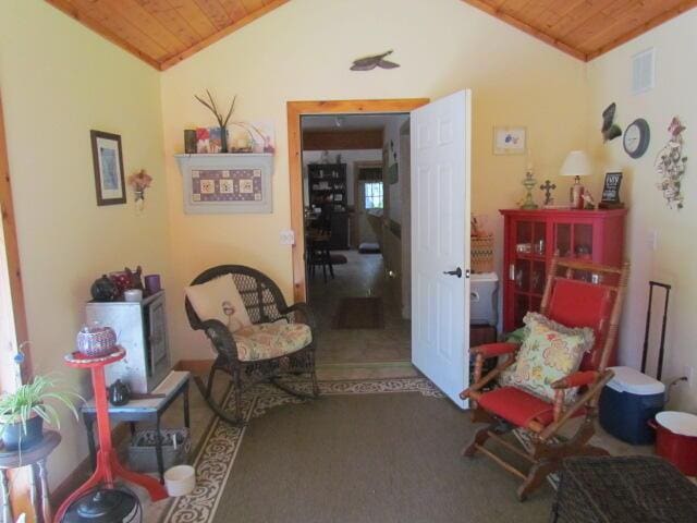 living area with visible vents, carpet, wood ceiling, and vaulted ceiling