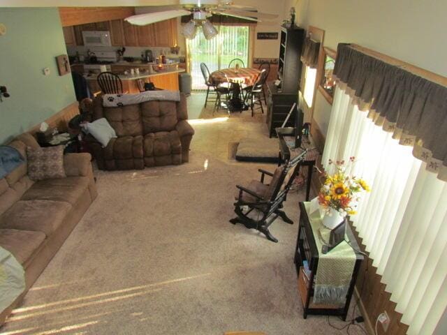 living area with light carpet and ceiling fan