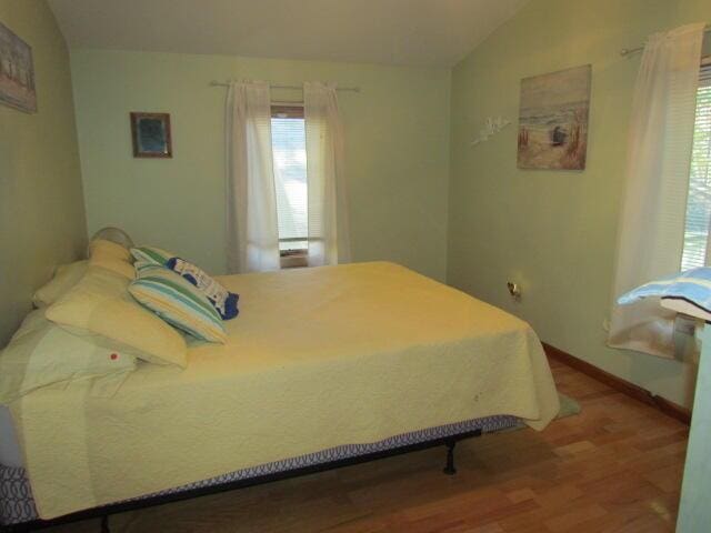 bedroom with baseboards, lofted ceiling, and wood finished floors