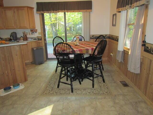 dining space featuring a wainscoted wall, wood walls, and visible vents