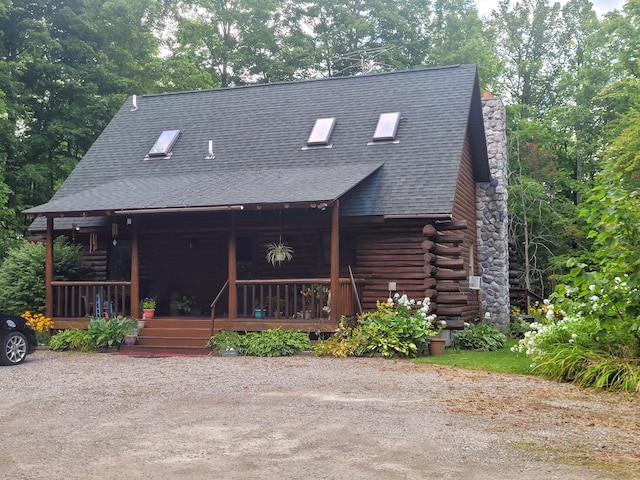 log home with log siding, covered porch, a chimney, and a shingled roof