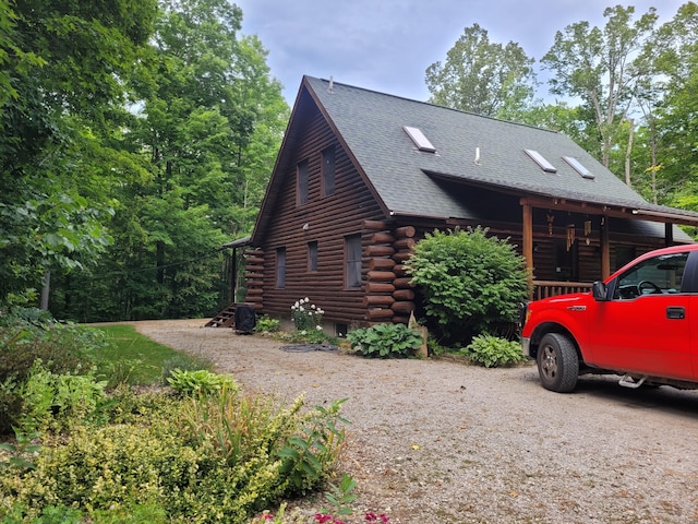 view of side of home with log siding and a shingled roof