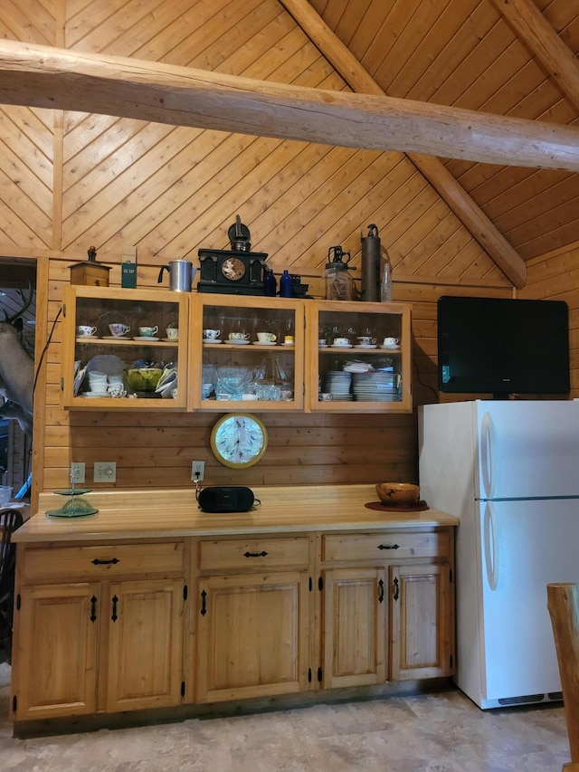 kitchen featuring lofted ceiling with beams, light countertops, wood walls, and freestanding refrigerator