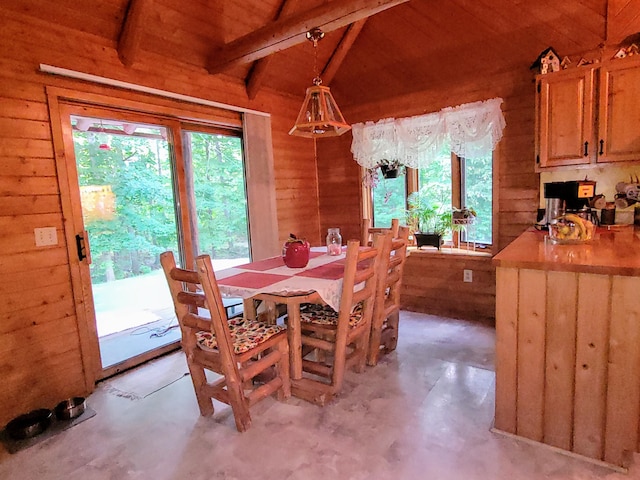 dining space with wood ceiling, wood walls, vaulted ceiling with beams, and concrete floors