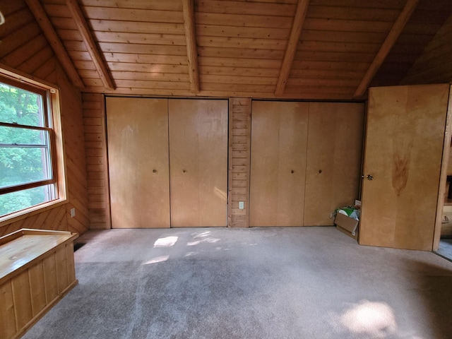 unfurnished bedroom with carpet flooring, wood ceiling, lofted ceiling with beams, and wooden walls