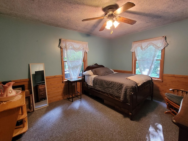 bedroom featuring a wainscoted wall, multiple windows, and wood walls