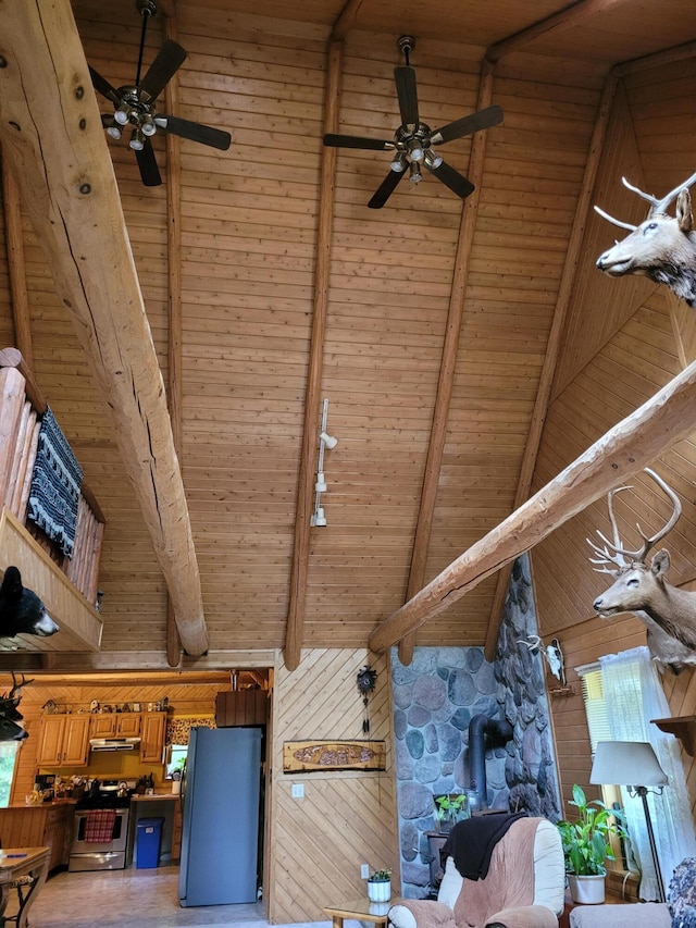 interior details featuring a ceiling fan, stainless steel electric stove, freestanding refrigerator, under cabinet range hood, and beamed ceiling